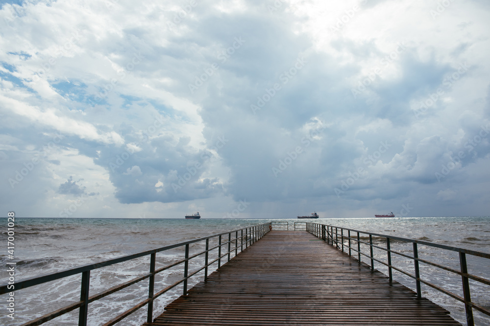 clouds over the sea. pier going into the distance