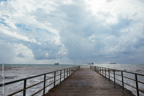 clouds over the sea. pier going into the distance