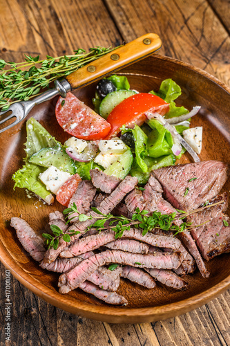 BBQ beef meat chop sirloin steak on a wooden plate with vegetable salad. wooden background. Top view