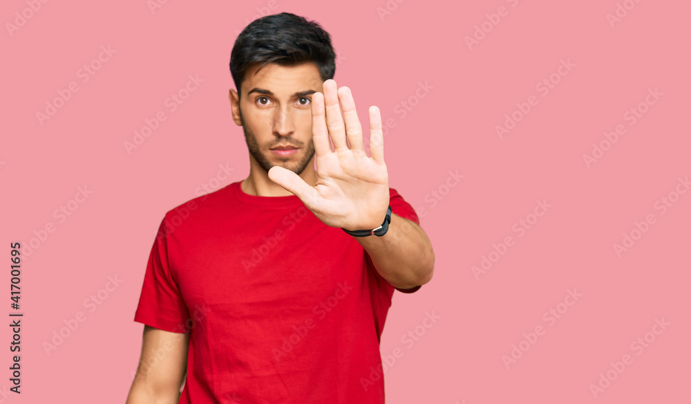 Young handsome man wearing casual red tshirt doing stop sing with palm of the hand. warning expression with negative and serious gesture on the face. Young handsome man wearing casual red tshirt doing stop sing with palm of the hand. warning expression with negative and serious gesture on the face.