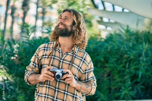 Young caucasian tourist man smiling happy using vintage camera at the park.