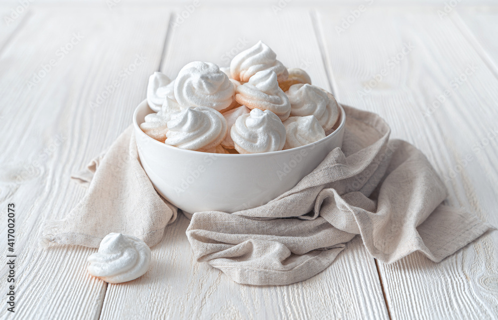 The white meringue cakes on the plate are wrapped in a linen napkin. The white meringue cakes on the plate are wrapped in a linen napkin.