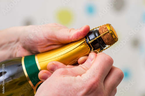 Mans hands are opening the bottle of champagne alcohol and wine drink on party celebration event. A man is opening the champagne bottle