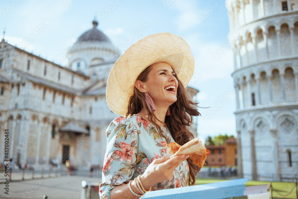 smiling young woman in floral dress with pizza and hat