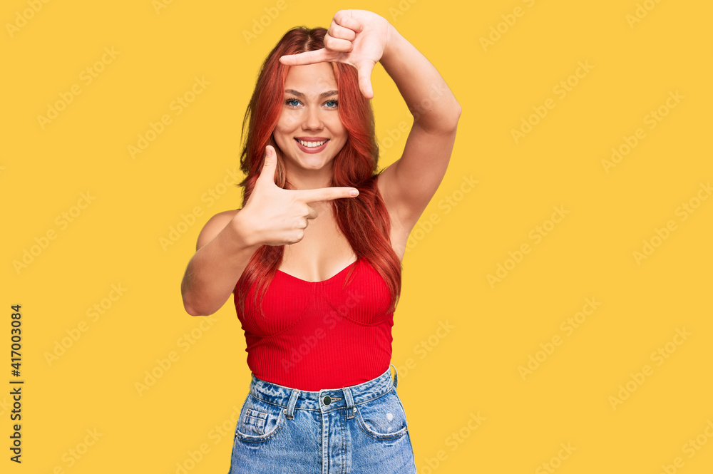 Young redhead woman wearing casual clothes smiling making frame with hands and fingers with happy face. creativity and photography concept. Young redhead woman wearing casual clothes smiling making frame with hands and fingers with happy face. creativity and photography concept.
