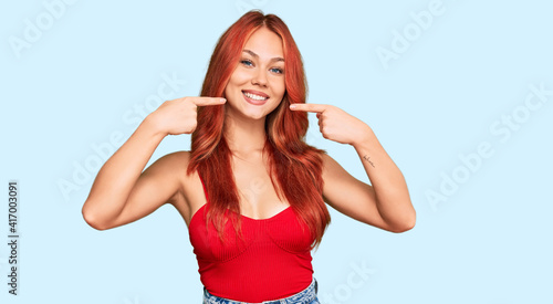 Young redhead woman wearing casual clothes smiling cheerful showing and pointing with fingers teeth and mouth. dental health concept.