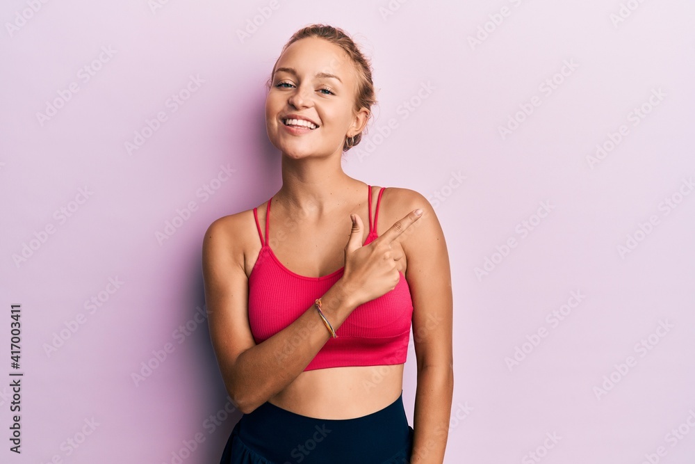 Fototapeta premium Beautiful caucasian woman wearing sportswear cheerful with a smile of face pointing with hand and finger up to the side with happy and natural expression on face