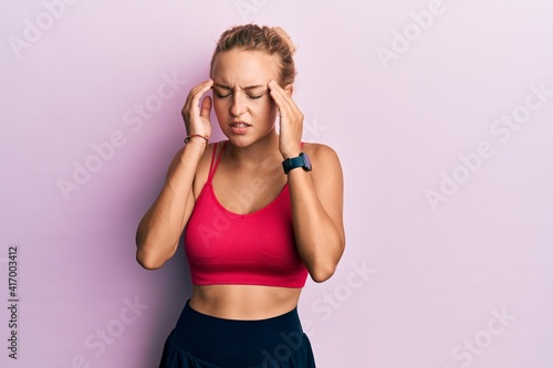 Beautiful caucasian woman wearing sportswear with hand on head for pain in head because stress. suffering migraine.