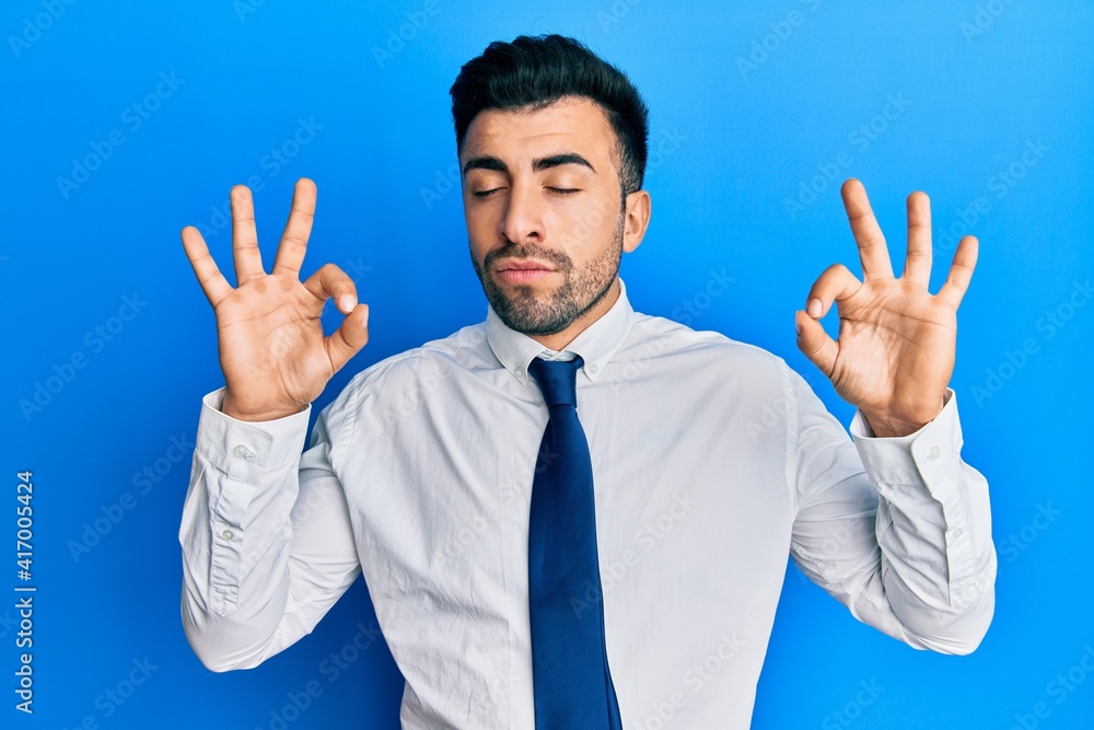 Young hispanic man wearing business clothes relax and smiling with eyes closed doing meditation gesture with fingers. yoga concept.