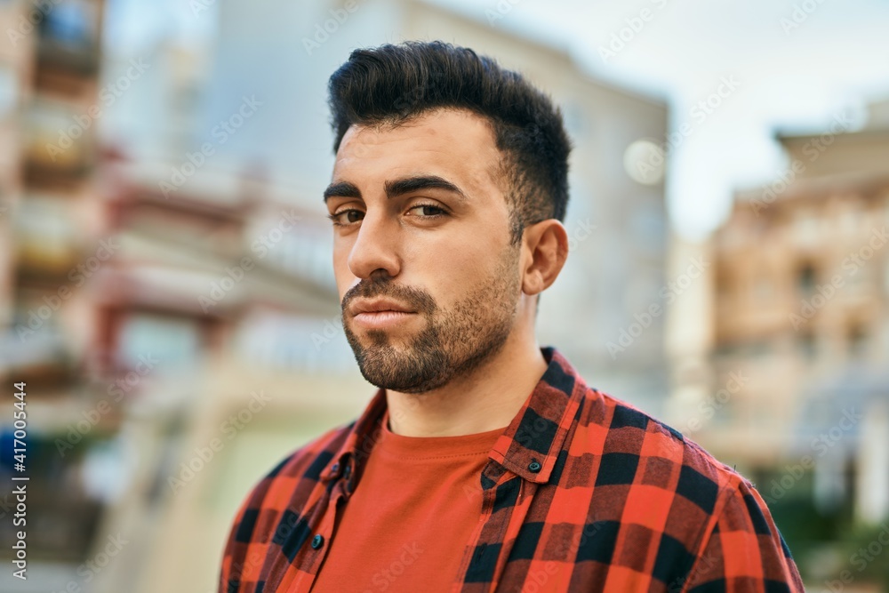 Young hispanic man with serious expression standing at the city. Young hispanic man with serious expression standing at the city.