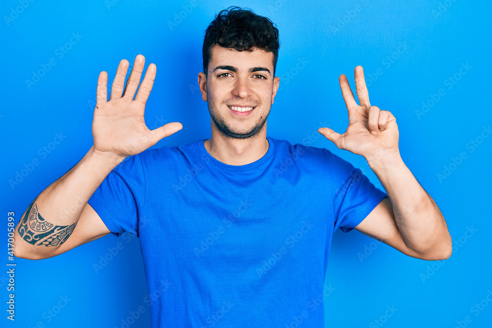 Young hispanic man wearing casual blue t shirt showing and pointing up with fingers number eight while smiling confident and happy. Young hispanic man wearing casual blue t shirt showing and pointing up with fingers number eight while smiling confident and happy.