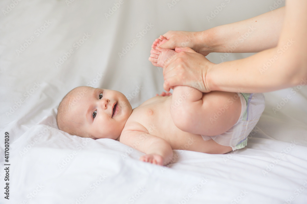 Happy infant girl doing baby massage by his mother at home. Newborn child about 5 months old Happy infant girl doing baby massage by his mother at home. Newborn child about 5 months old