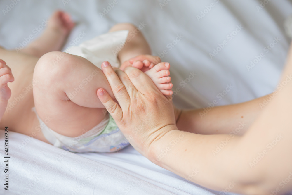 Happy infant girl doing baby massage by his mother at home. Newborn child about 5 months old Happy infant girl doing baby massage by his mother at home. Newborn child about 5 months old