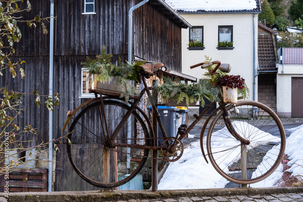 An old, rusty bicycle being used as a plant decoration in a small German village
