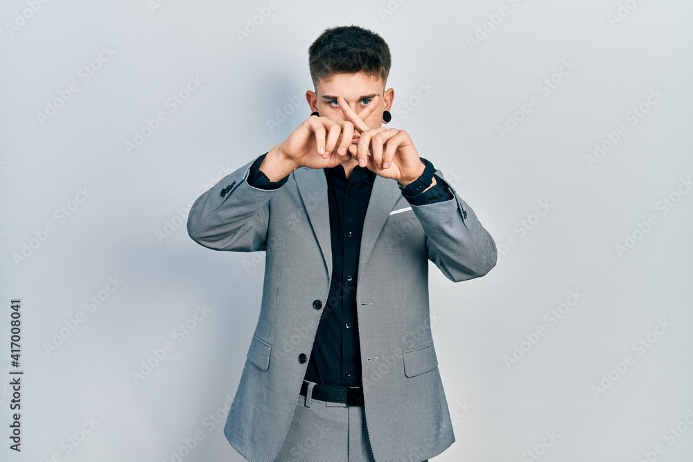 Young caucasian boy with ears dilation wearing business jacket rejection expression crossing fingers doing negative sign Young caucasian boy with ears dilation wearing business jacket rejection expression crossing fingers doing negative sign