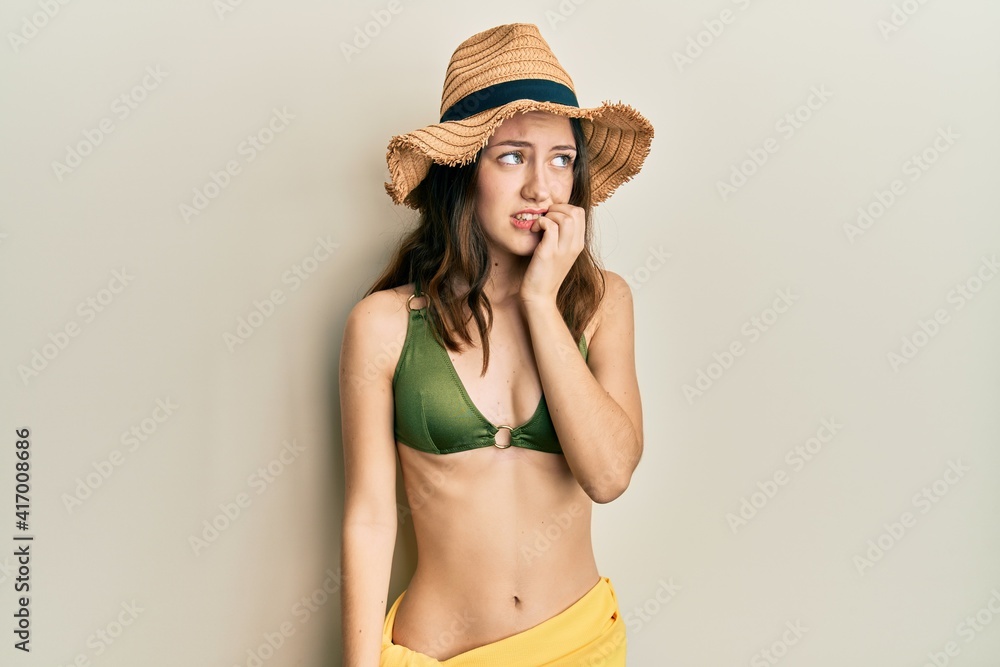 Young brunette woman wearing bikini looking stressed and nervous with hands on mouth biting nails. anxiety problem. Young brunette woman wearing bikini looking stressed and nervous with hands on mouth biting nails. anxiety problem.