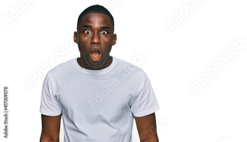 Young african american man wearing casual white t shirt afraid and shocked with surprise and amazed expression, fear and excited face.