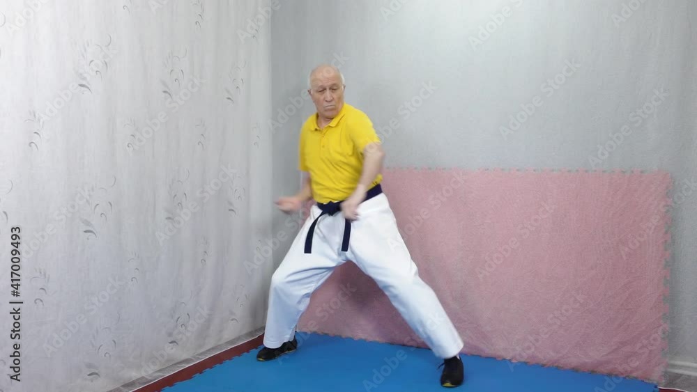 Old male athlete in yellow t-shirt trains formal exercises Old male athlete in yellow t-shirt trains formal exercises