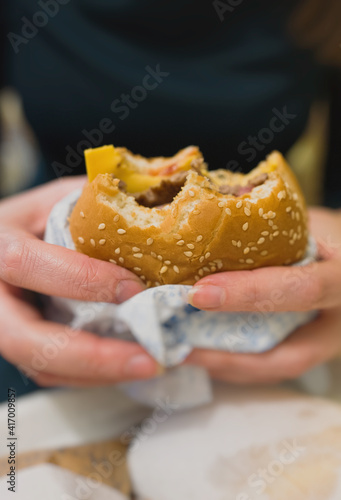 Woman holding hamburger in fast food restaurant.