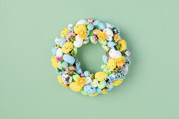 Handmade diy home interior decoration wreath with colorful easter eggs over green background