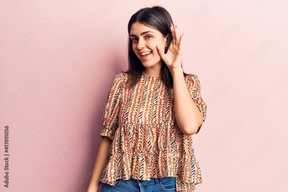 Young beautiful girl wearing casual t shirt smiling with hand over ear listening and hearing to rumor or gossip. deafness concept.
