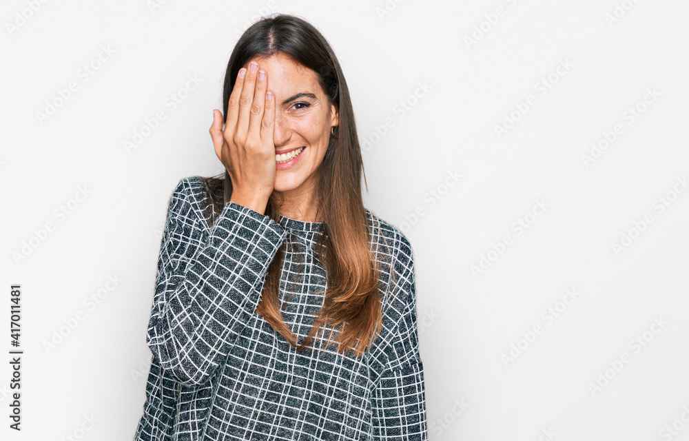 Young beautiful woman wearing casual clothes covering one eye with hand, confident smile on face and surprise emotion. Young beautiful woman wearing casual clothes covering one eye with hand, confident smile on face and surprise emotion.