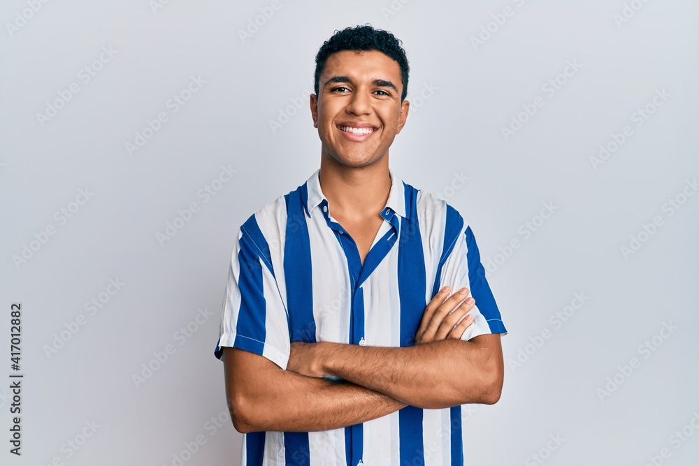 Young arab man wearing casual clothes happy face smiling with crossed arms looking at the camera. positive person. Young arab man wearing casual clothes happy face smiling with crossed arms looking at the camera. positive person.