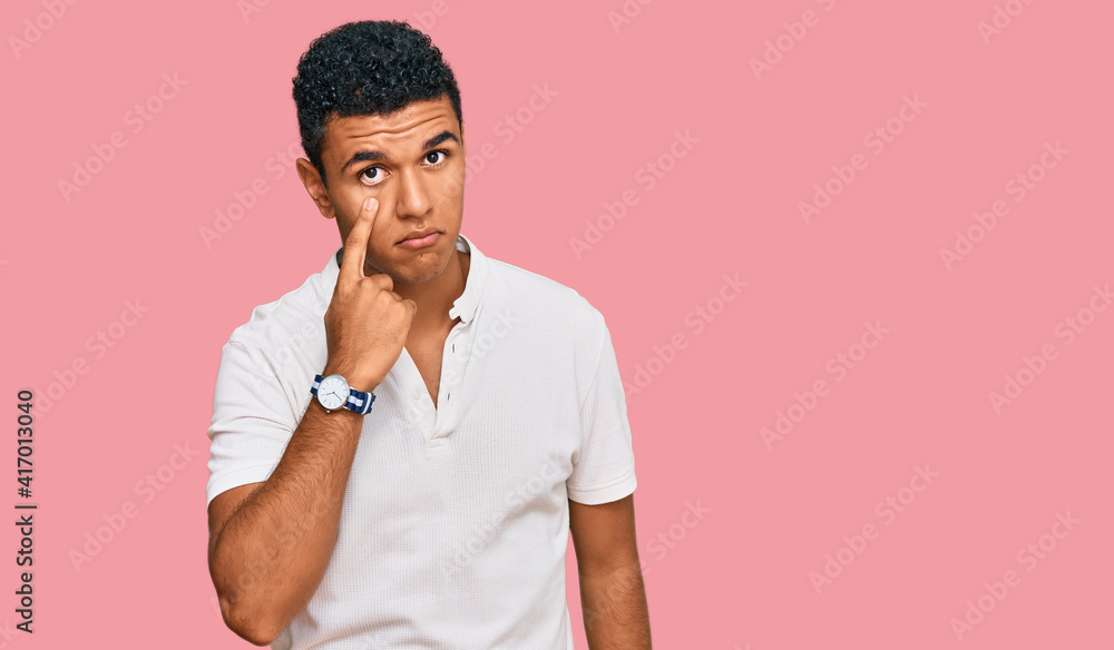 Young arab man wearing casual clothes pointing to the eye watching you gesture, suspicious expression Young arab man wearing casual clothes pointing to the eye watching you gesture, suspicious expression