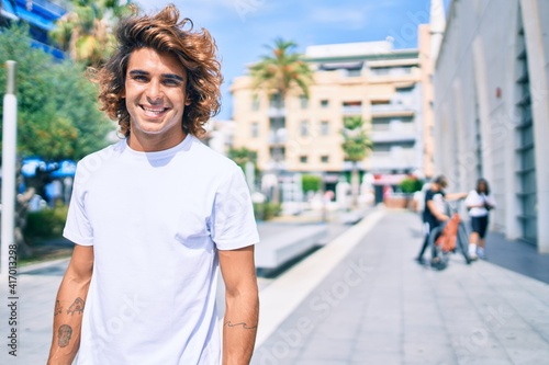 Young handsome hispanic man smiling happy walking at street of city