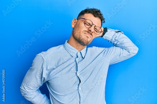 Young hispanic man wearing casual clothes and glasses suffering of neck ache injury, touching neck with hand, muscular pain