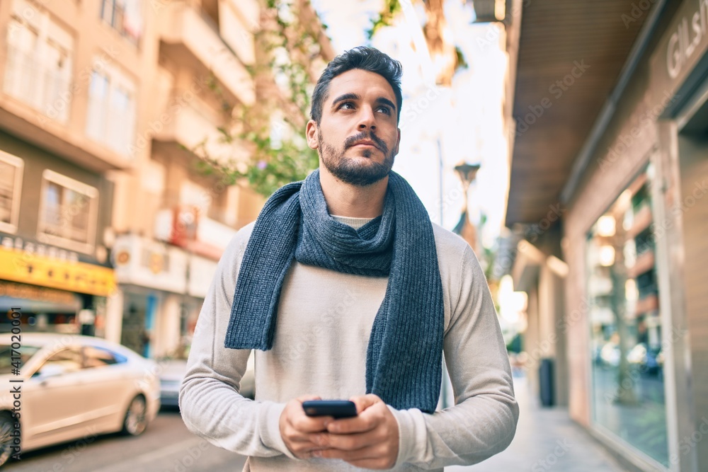 Young hispanic man with serious expression using smartphone at the city. Young hispanic man with serious expression using smartphone at the city.