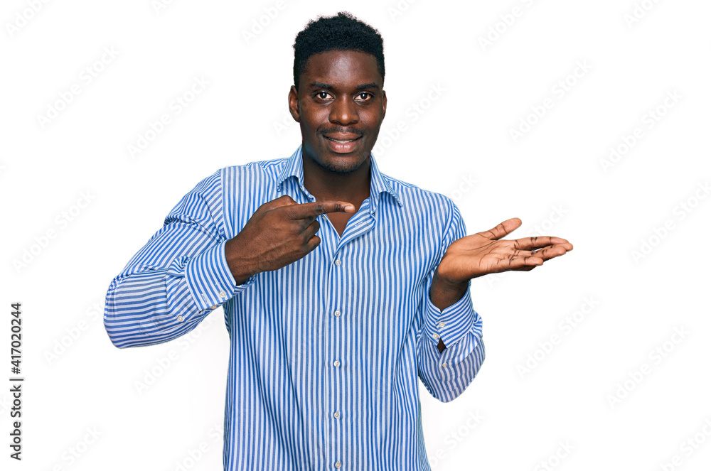 Handsome business black man wearing casual striped t shirt amazed and smiling to the camera while presenting with hand and pointing with finger. Handsome business black man wearing casual striped t shirt amazed and smiling to the camera while presenting with hand and pointing with finger.