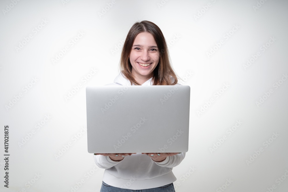 Young cute woman is holding an opened laptop with both hands, studio photo on white background Young cute woman is holding an opened laptop with both hands, studio photo on white background