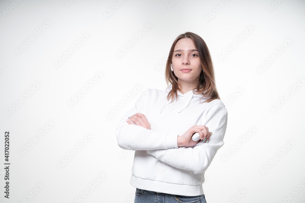 Cute young student with long fair hair is looking in a camera, standing with her hands folded, white background, studio photo Cute young student with long fair hair is looking in a camera, standing with her hands folded, white background, studio photo