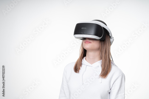 Profile portrait of a teenage girl in VR glasses, studio, white background