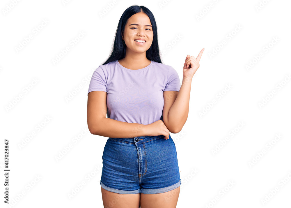 Young beautiful asian girl wearing casual clothes smiling happy pointing with hand and finger to the side Young beautiful asian girl wearing casual clothes smiling happy pointing with hand and finger to the side