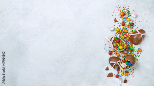 Easter banner with chocolate eggs and decorative sugar sprinkles on light background