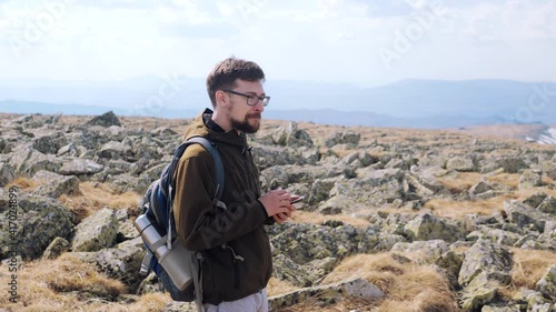 Young man backpacker discovering nature in spring mountains with compass and gps app on smartphone. Travel lifestyle concept. Male hiker using mobile phone and compass to orientate in mountains.