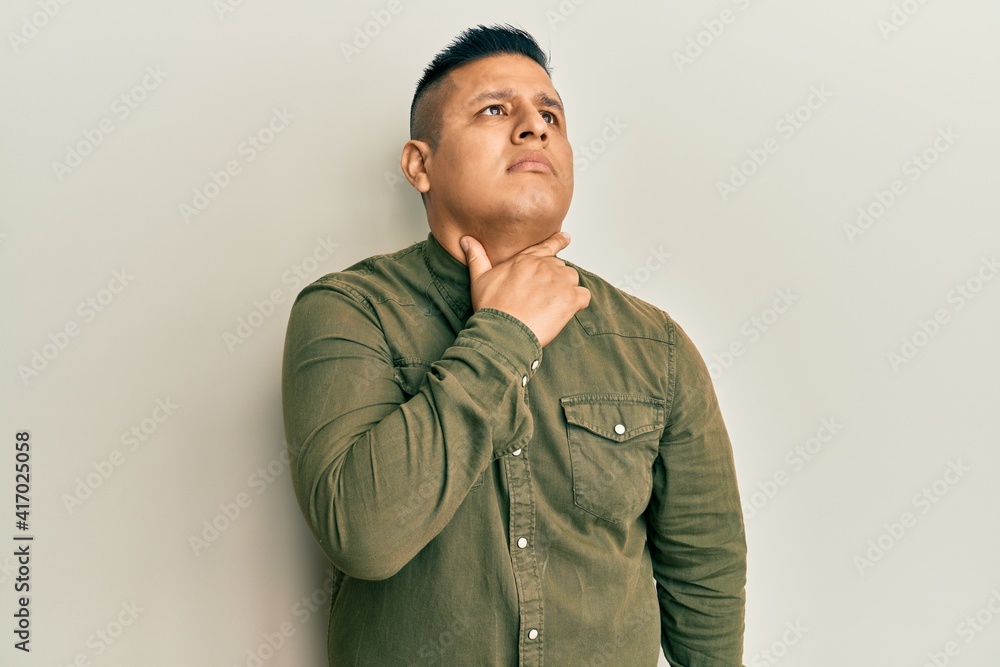 Fototapeta premium Young latin man wearing casual clothes touching painful neck, sore throat for flu, clod and infection