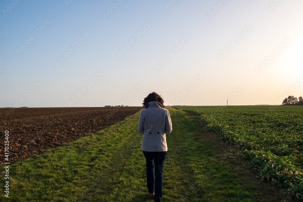 Girl with a coat between two field at dawn Girl with a coat between two field at dawn