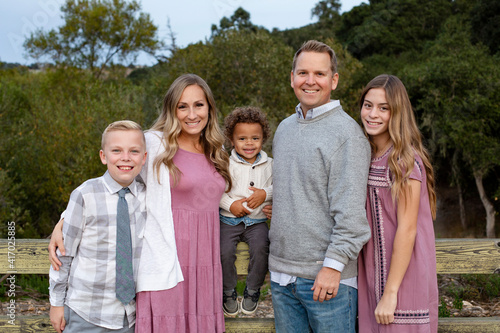 Smiling and happy diverse group with a mixed race adopted baby boy and two other children. Attractive people standing together