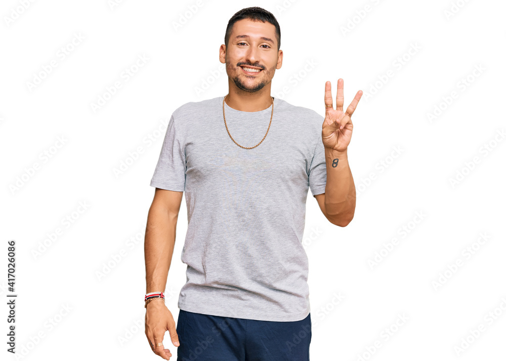Fototapeta premium Handsome man with tattoos wearing 90s style showing and pointing up with fingers number three while smiling confident and happy.