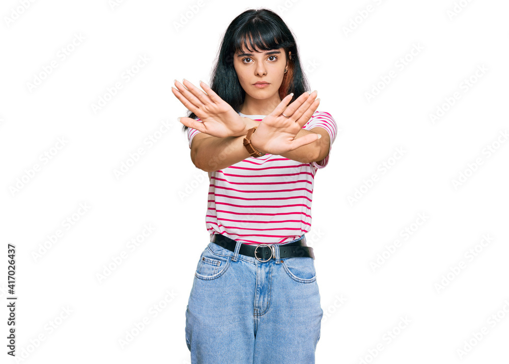 Young hispanic girl wearing casual clothes rejection expression crossing arms and palms doing negative sign, angry face Young hispanic girl wearing casual clothes rejection expression crossing arms and palms doing negative sign, angry face