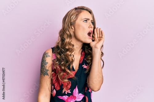 Young blonde girl wearing casual clothes shouting and screaming loud to side with hand on mouth. communication concept.