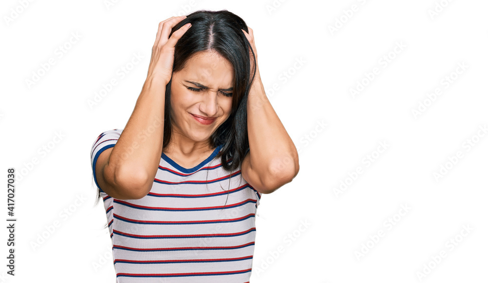 Young hispanic girl wearing casual striped t shirt suffering from headache desperate and stressed because pain and migraine. hands on head. Young hispanic girl wearing casual striped t shirt suffering from headache desperate and stressed because pain and migraine. hands on head.