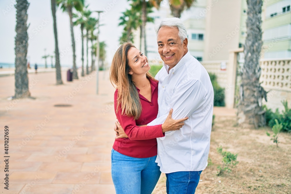 Middle age hispanic couple smiling happy and hugging walking at street. Middle age hispanic couple smiling happy and hugging walking at street.