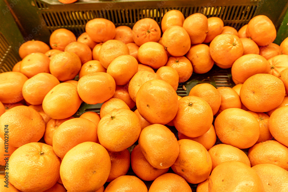 Fresh tangerines in the store close-up. Crates full of ripe mandarin and clementines oranges for sale at the counter