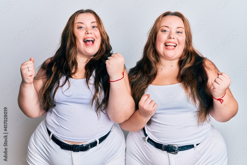 Plus size caucasian sisters woman wearing casual white clothes celebrating surprised and amazed for success with arms raised and open eyes. winner concept. Plus size caucasian sisters woman wearing casual white clothes celebrating surprised and amazed for success with arms raised and open eyes. winner concept.