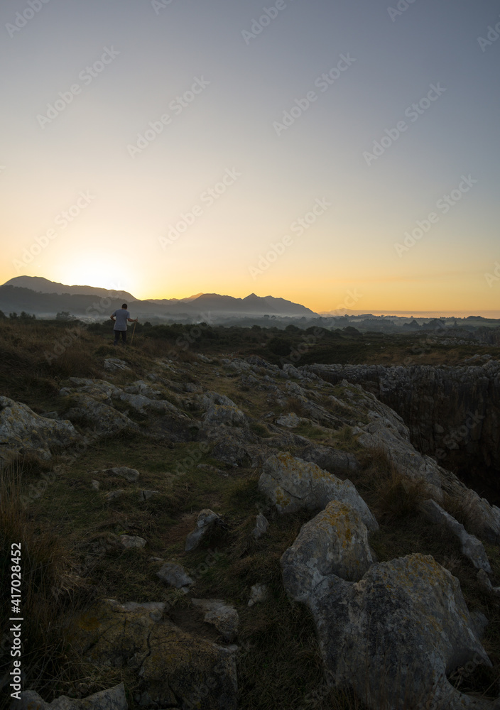 man walking in the field next to the sea 2