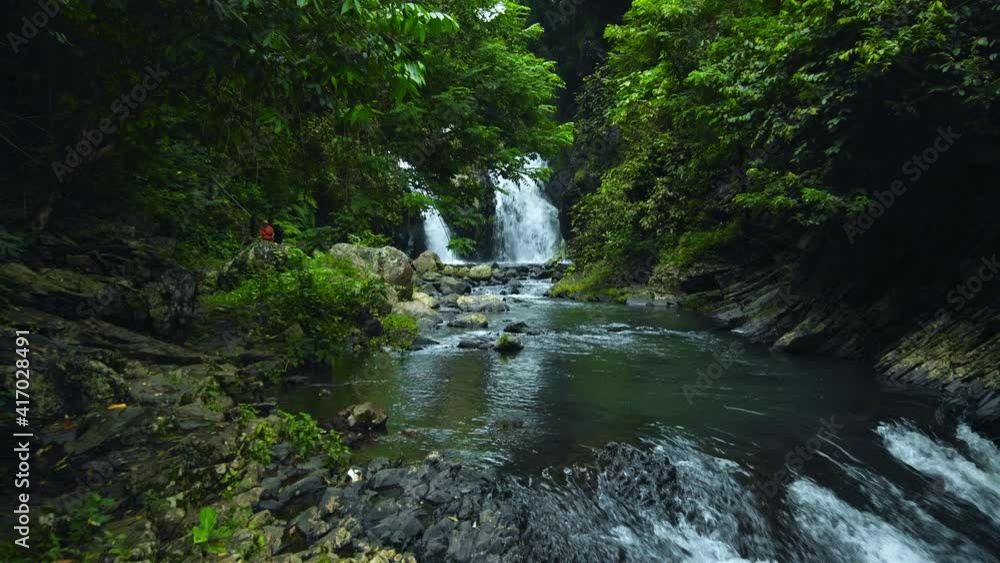 waterfall with rocks among tropical jungle with green plants and trees and water falling down into the river waterfall with rocks among tropical jungle with green plants and trees and water falling down into the river